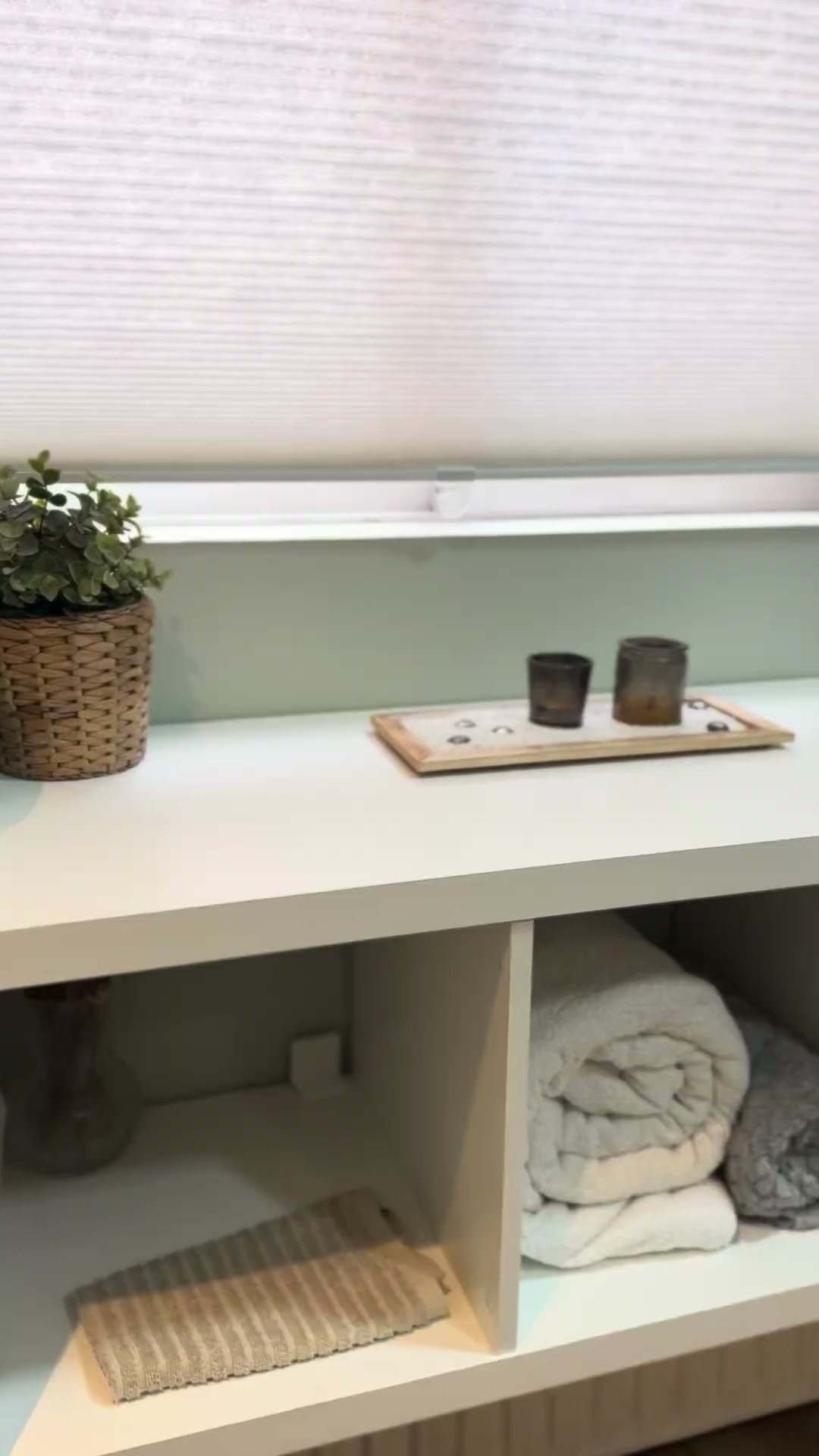 Estantería blanca con toallas dobladas y una planta