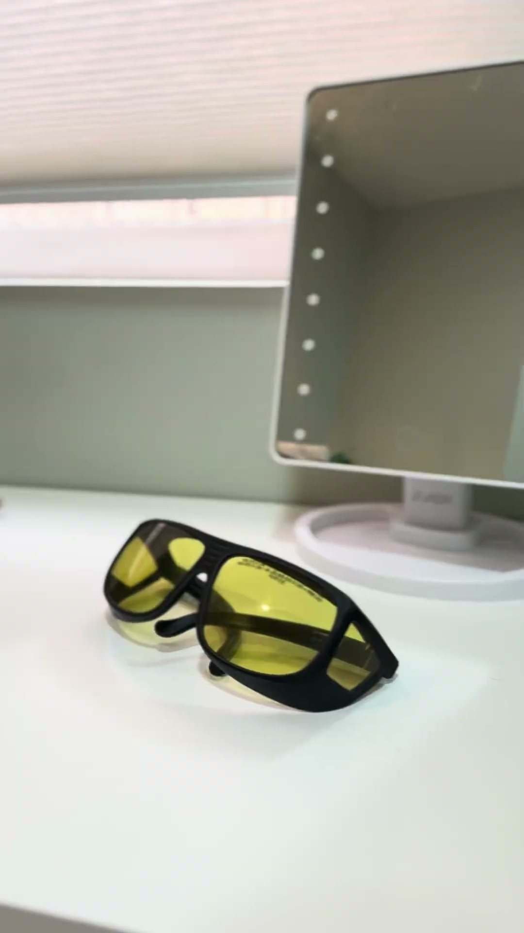 Gafas de protección delante de un espejo con luces en la cabina